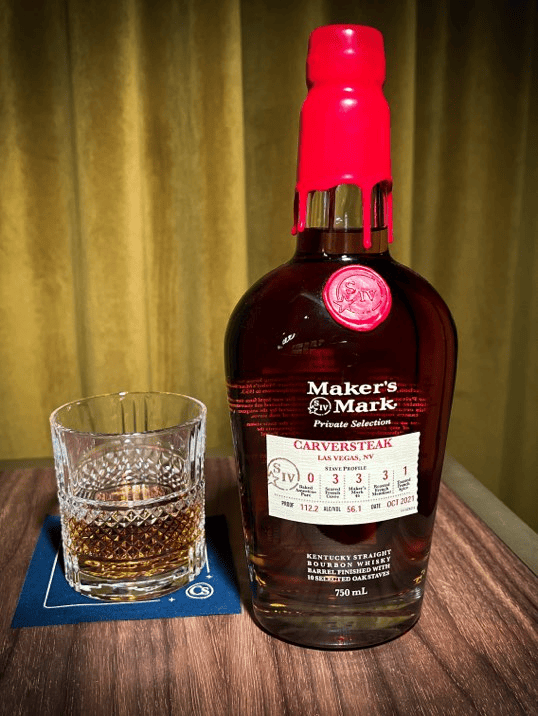 What Is the Best Steak Restaurant on the Strip? Maker's Mark Private Selection bourbon bottle with a red wax seal beside a glass of whiskey on a coaster.