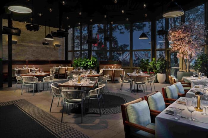 Elegant restaurant dining area with large windows, modern furnishings, and decorative lighting, set for evening service.