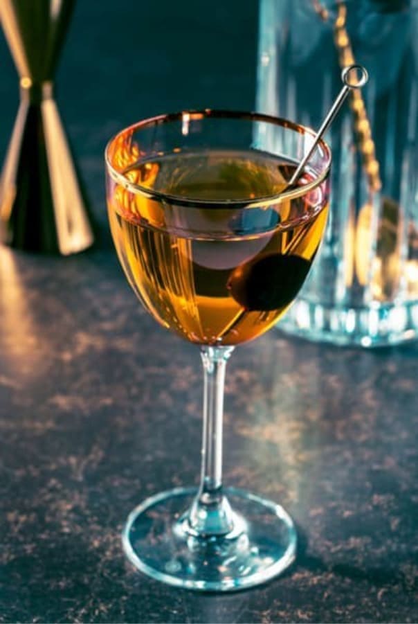 Martini cocktail with olive garnish in a coupe glass on a bar surface
