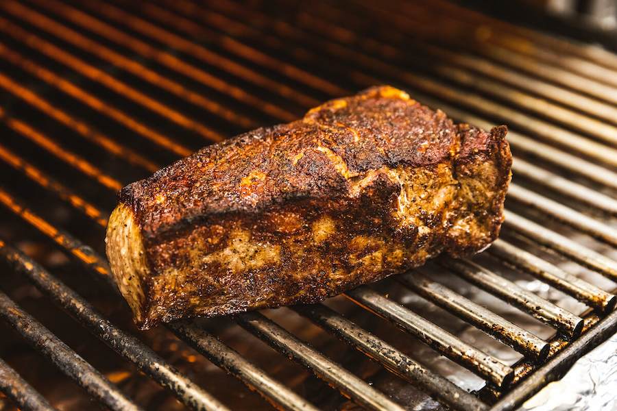 Thick-cut grilled steak resting on hot metal grill grates with visible char marks.
